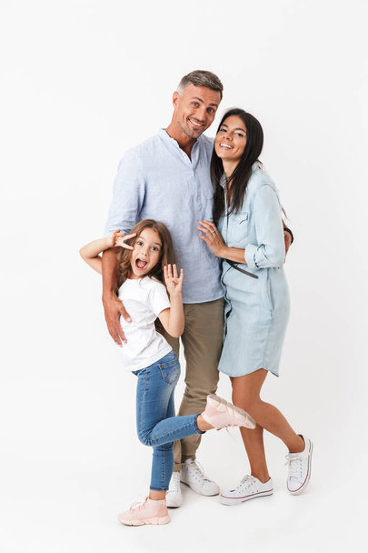 Portrait of a happy family father, mother, little daughter hugging isolated over gray background - Fotoğraf, Görsel