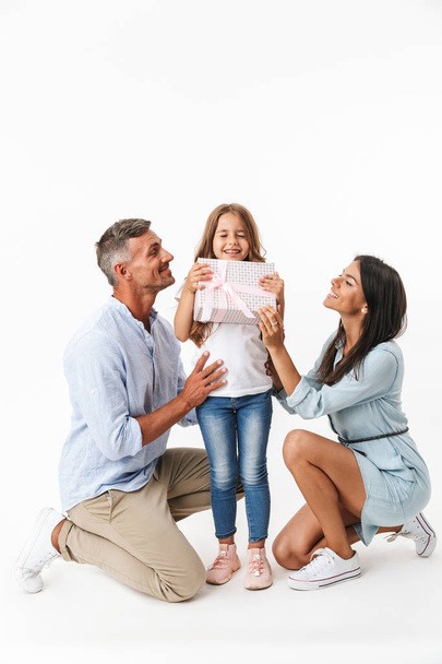 Portrait of a joyful family father, mother, little daughter celebrating together, little girl holding present box isolated over gray background - Foto, immagini