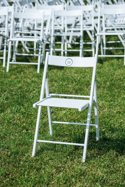 sillas blancas vacías con números sobre hierba verde
 - Foto, Imagen