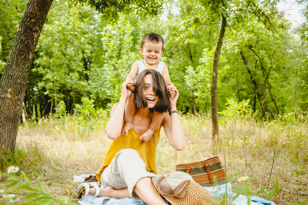 happy mother holding son on shoulders at picnic  - Φωτογραφία, εικόνα
