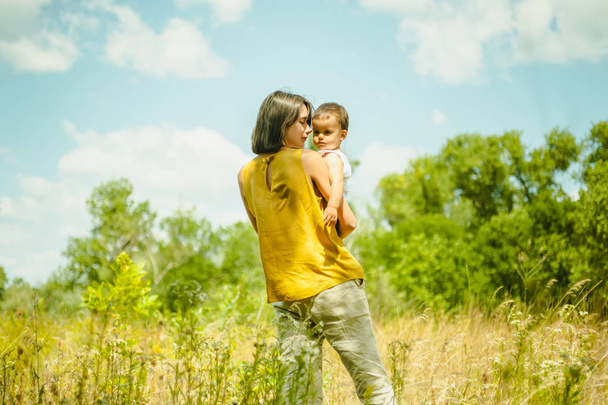 madre sosteniendo hijo en el campo en día soleado
 - Foto, imagen