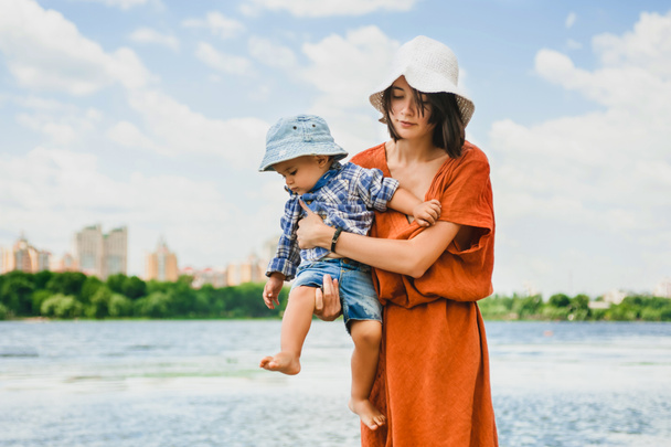 mother holding son near river in summer - Foto, Bild