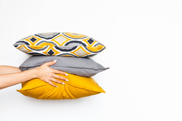 Colorful pillows in women's hands on a white isolated background, the concept of home comfort - Fotoğraf, Görsel