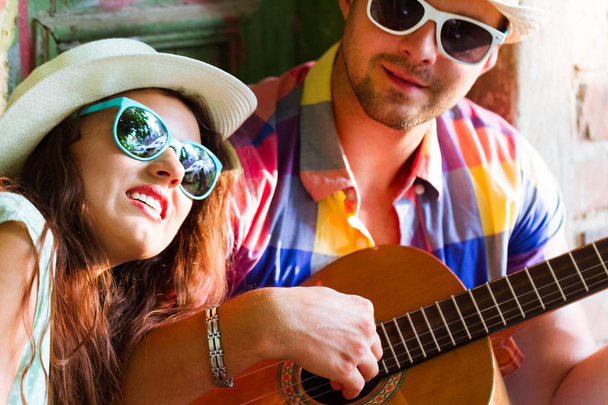 Happy smiling couple in sunglass and hat  with guitar drinking juice spending carefree time together. Travel and love concept - Foto, Imagem