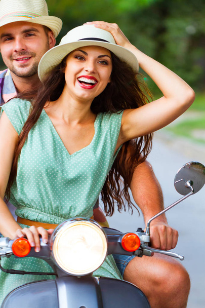 Young happy couple in love riding a vintage scooter in the street wearing hats. Holiday and travel concept - Photo, Image