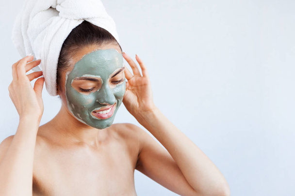 Young beautiful woman in face mask of therapeutic blue mud. Spa treatment, self care and healthy skin. Copy space, white background - Fotó, kép