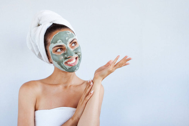 Young beautiful woman in face mask of therapeutic blue mud. Spa treatment, self care and healthy skin. Copy space, white background - Zdjęcie, obraz