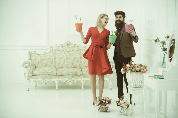 Flower concept. Sensual woman and bearded man smile with flowers in pots. Flower shop. Say it with flowers - Photo, Image