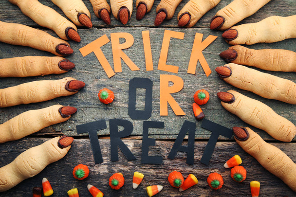 Halloween finger cookies with inscription and candies on grey wooden table - 写真・画像