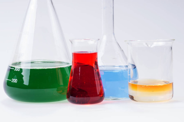 glas laboratoriumapparatuur met kleur water op tafel - Foto, afbeelding