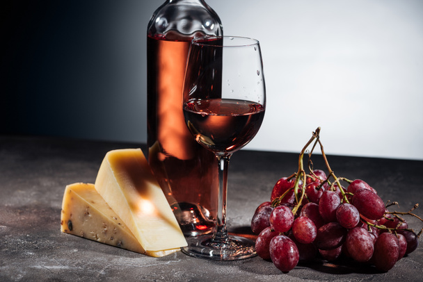 γυαλί μπουκάλι κρασί, τυριά, σταφύλια σε γκρι - Φωτογραφία, εικόνα