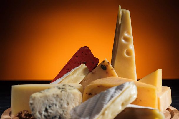 different types of tasty cheeses on orange - Photo, Image