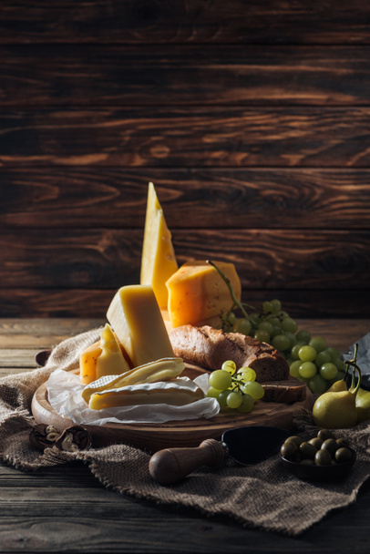 tasty different types of cheeses, grapes and pears on table in kitchen - Photo, Image