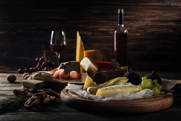 erityyppisiä juustoja ja hedelmiä leikkuulaudalla
 - Valokuva, kuva