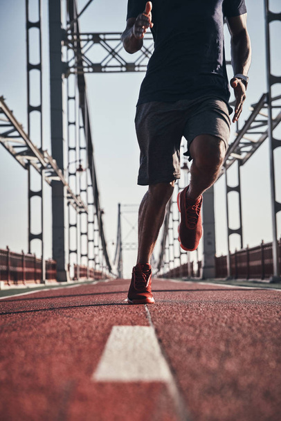 man jogging on bridge outdoors, low angle view, cropped image - Foto, Imagen