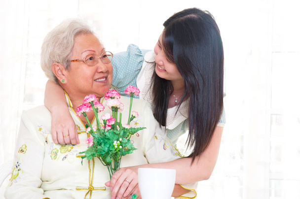 asiatische Seniorin erhielt Nelkenblume als Muttertagsgeschenk von Tochter - Foto, Bild