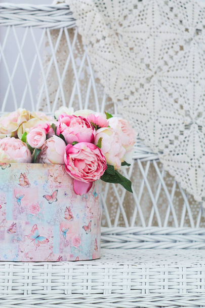 Корзина с цветами на белой плетеной скамейке
 - Фото, изображение