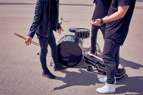 partial view of rock band in black clothing standing near musical instruments on street - Photo, Image
