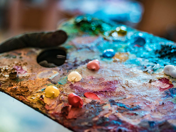 Wooden art palette with oil paints. Mixing colors together. Artistic instrument with many colors. Working tool with squeezed out tubes of paint. - Fotoğraf, Görsel