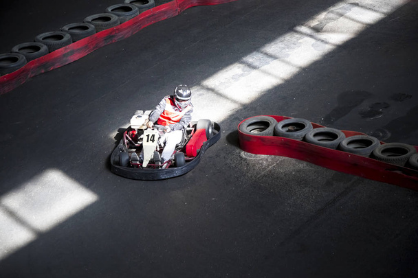 Riding on karting on the auto track. The young guy competes at the wheel of a carting. - Fotó, kép
