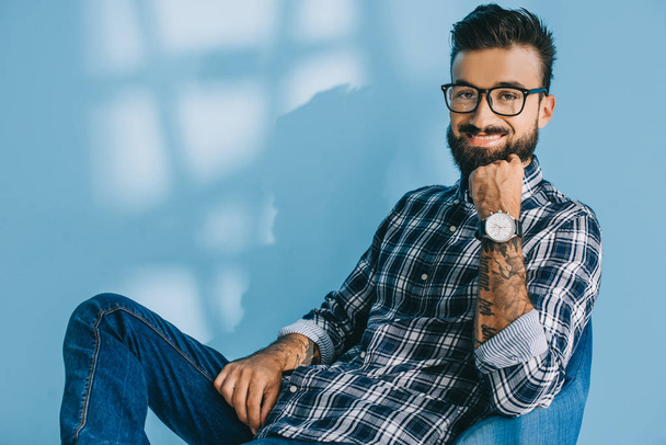 handsome bearded man in checkered shirt, on blue - Foto, afbeelding