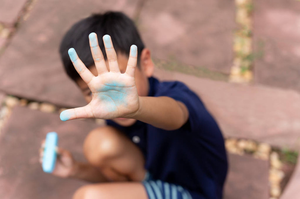Petit garçon avec la main sale de craie bleue après le dessin
. - Photo, image