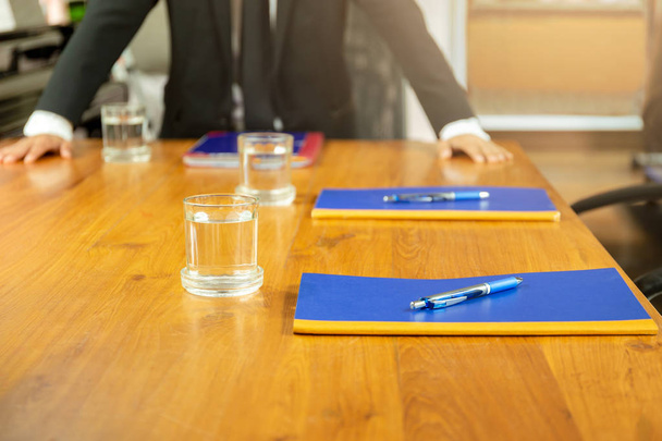 Businessman in conference room with glasses of water and pen and notebook on wooden table. - Φωτογραφία, εικόνα
