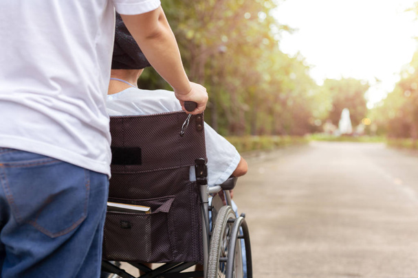 Caretaker and daughter spending time outdoor with patient in wheelchair. - Foto, Bild