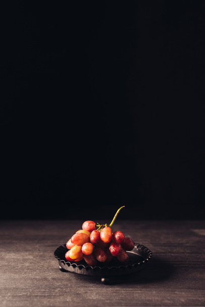 close-up view of fresh ripe red grapes on wooden table on black  - Фото, зображення