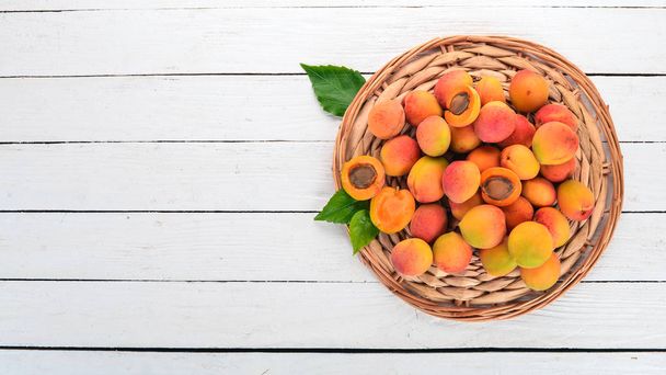 Fresh apricots with leaves On a white wooden background. Top view. Free space for your text. - Photo, image