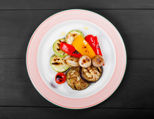 野菜、きのこ、トマト、木製の背景に皿にナスのグリル。健康食品. - 写真・画像