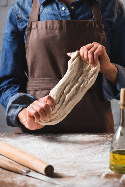cropped shot of woman in apron kneading dough for pizza - Фото, зображення