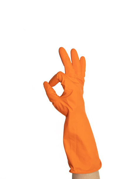 Ok sign of orange rubber gloves. Preparing for cleaning. Hands clean after cleaning. Squeaky people. Wash floors, wash dishes. Rubber gloves on the hand. Rubber gloves on a hand on a white background. Rubber gloves for cleaning. - Photo, Image