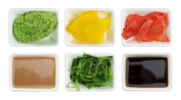 Японские суши. Соевый соус, васаби, маринованный имбирь, чука, кунжутный соус и маринованная редиска изолированы на белом фоне
 - Фото, изображение