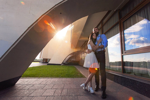 A beautiful couple in the rays of the sunset near the building. - Fotoğraf, Görsel