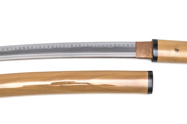 Больше деталей лезвия японского меча возле ножен на белом фоне. Изготовлен из премиальной стали под названием 'Tamahagane'
 - Фото, изображение