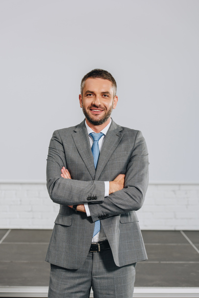 smiling handsome businessman with crossed arms looking at camera in hub - Photo, Image