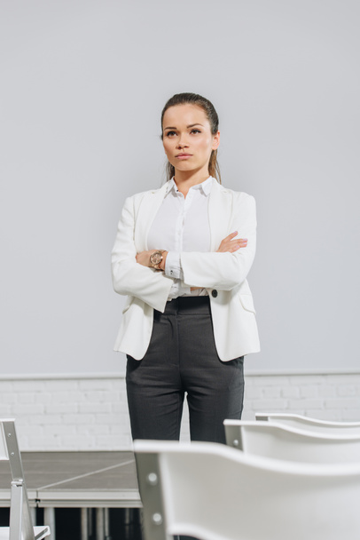 attractive serious businesswoman standing with crossed arms in hub - Foto, Bild
