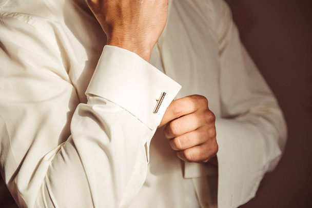 Człowiek w schludny, biała koszula, mocowanie ładne spinki do mankietów starannie na mankietach koszuli - Zdjęcie, obraz