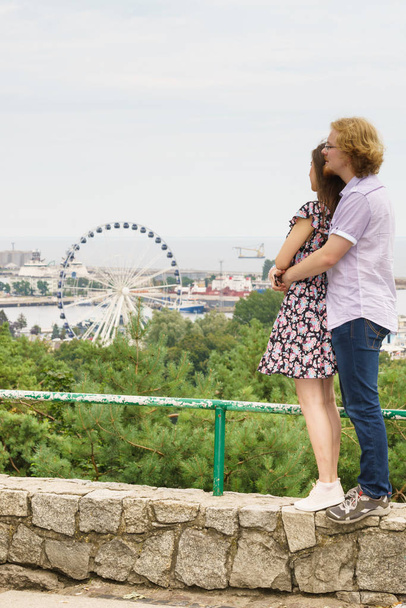 Man and woman having romantic date looking at city panorama view and ferris wheel outdoor. Couple romance moments concept. - Фото, изображение