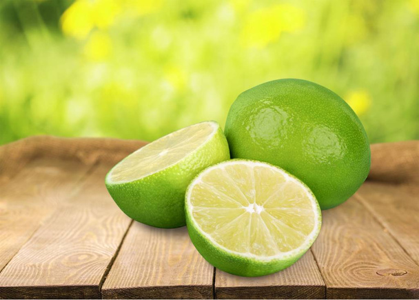 Fresh green limes on wooden table  - Foto, afbeelding