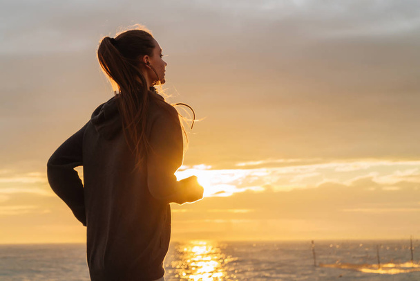 stubborn long-haired girl runs around the sea at sunset, wants to lose weight - Φωτογραφία, εικόνα