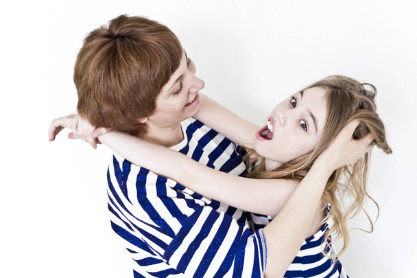 Happiest mother and daughter playing near white wall in striped clothes - 写真・画像