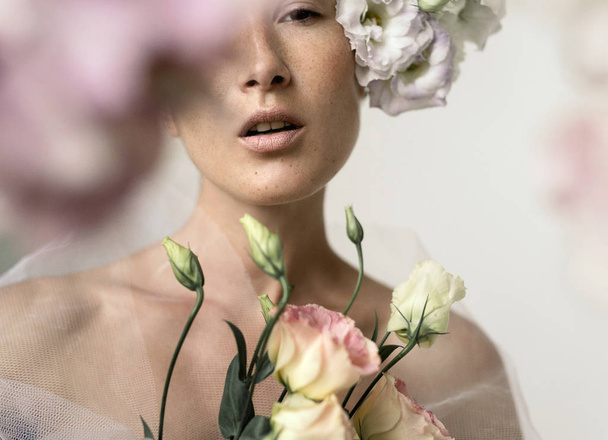 Portrait of gorgeous freckled young woman with eustoma flowers posing - Foto, immagini