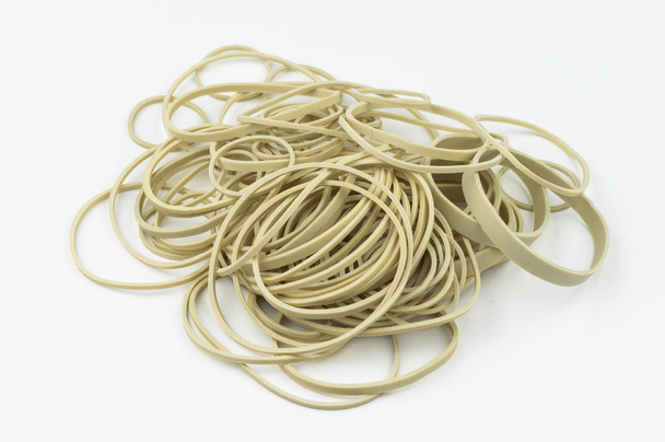 A stack of different sized latex, rubber bands on a white background ready for assorted uses in school, an office, or miscellaneous other environments. - Foto, Imagem