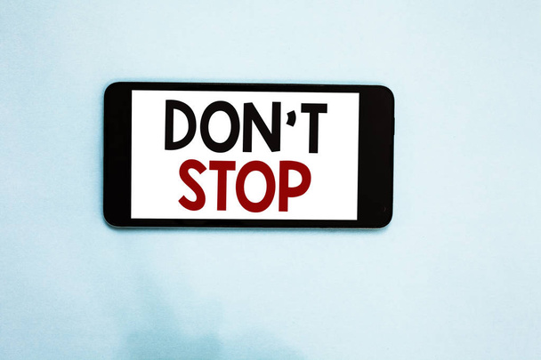 Textzeichen mit der Aufschrift "Don 't Stop". konzeptionelle Foto fortsetzen, was getan worden war, ohne eine Verzögerung Handy weißen Bildschirm über hellblauen Hintergrund Textnachrichten Apps - Foto, Bild