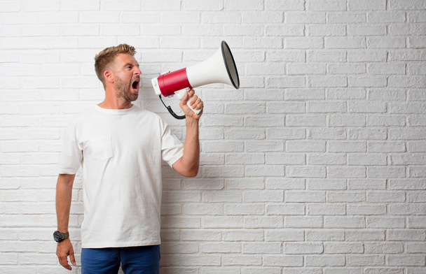 handsome blonde man shouting on a megaphone - Фото, зображення
