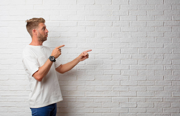handsome blonde man pointing to an empty place - Foto, afbeelding