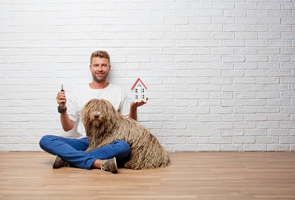handsome blonde man with a dog, house model and a keys - Фото, изображение