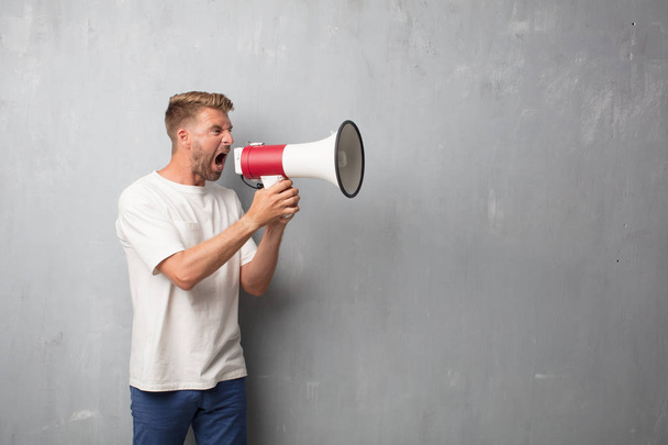 handsome blonde man shouting with a megaphone - 写真・画像